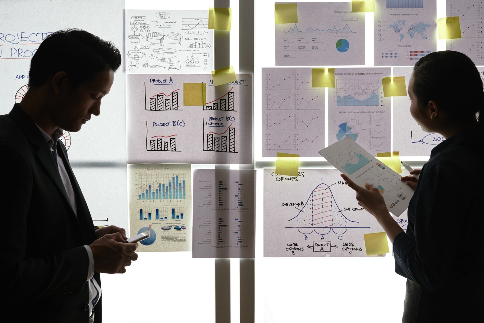 Business people working with different financial charts and graphs handing on glass wall
